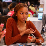 Student sitting at a table posing a question for their peers